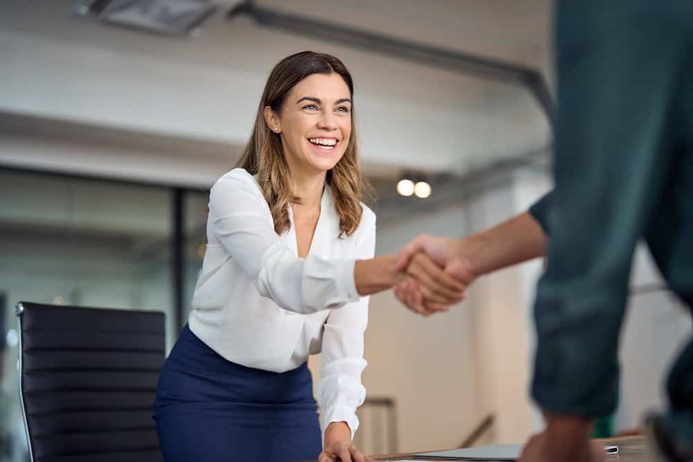 Profesional estrechando la mano durante una reunión de colaboración empresarial.